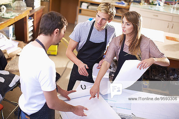 Drei Personen in einer Werkstatt zur Herstellung von Glasmalerei