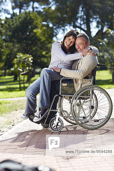 Frau umarmt Mann im Rollstuhl