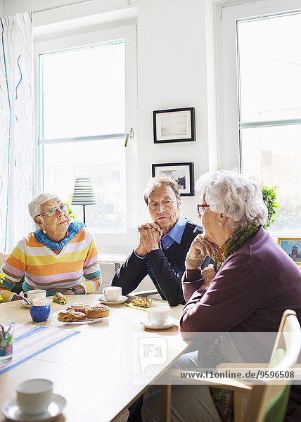 Senioren diskutieren am Frühstückstisch im Pflegeheim