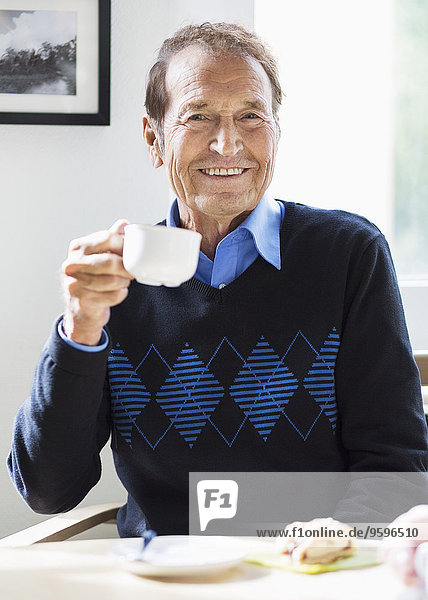 Porträt eines glücklichen älteren Mannes beim Kaffee im Pflegeheim