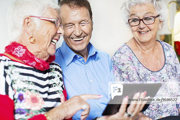 Glückliche Seniorenfreunde mit dem digitalen Tablett im Pflegeheim