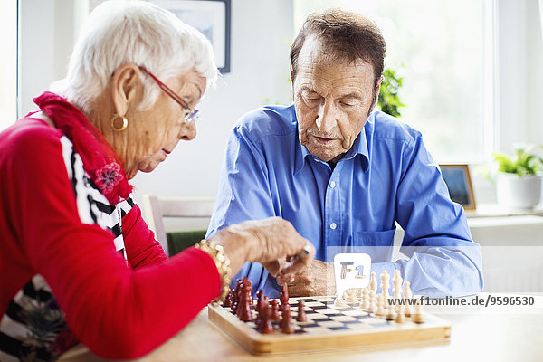 Seniorenpaar beim Schachspielen am Tisch im Pflegeheim
