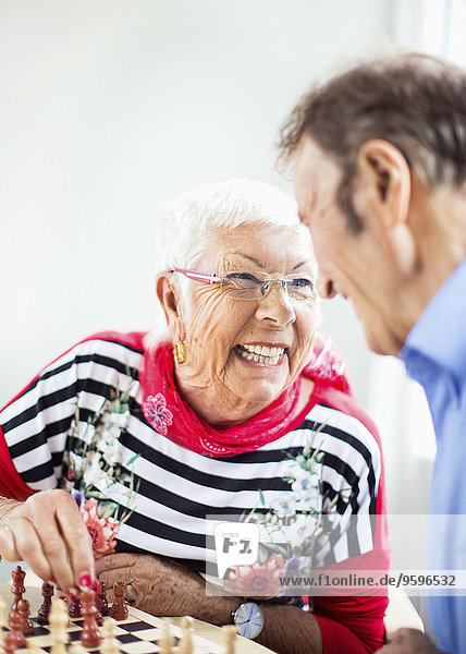 Glückliches älteres Paar  das sich beim Schachspielen im Pflegeheim ansieht.