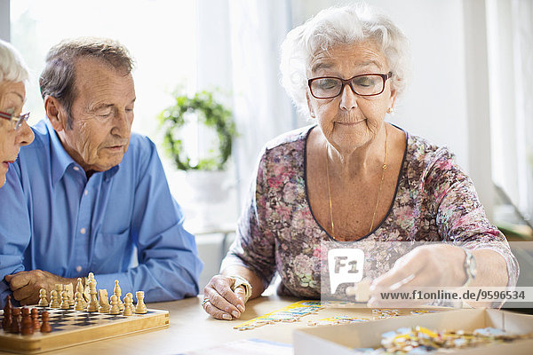 Senioren spielen Freizeitspiele am Tisch im Pflegeheim