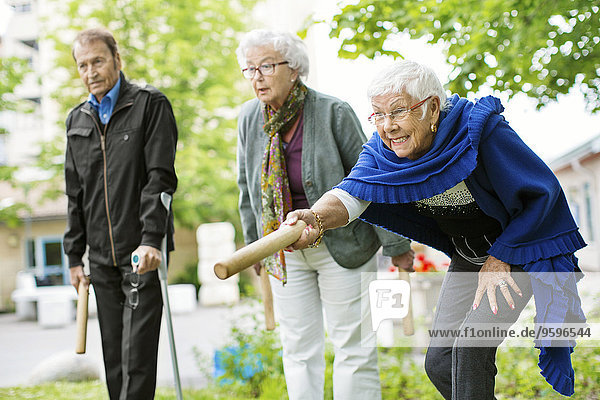 Glückliche Senioren beim Kubb-Spiel im Park