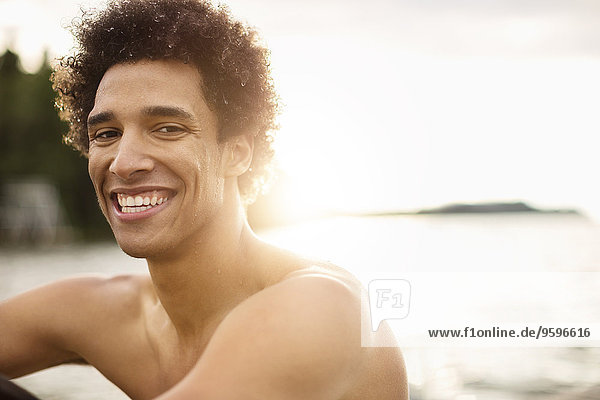 Porträt eines lächelnden jungen Mannes am Seeufer
