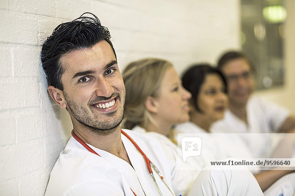 Porträt eines lächelnden Arztes mit Kolleginnen im Krankenhaus