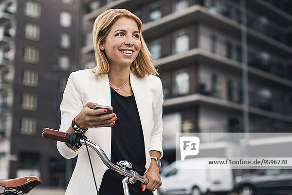 Lächelnde Geschäftsfrau mit Smartphone in der Stadt