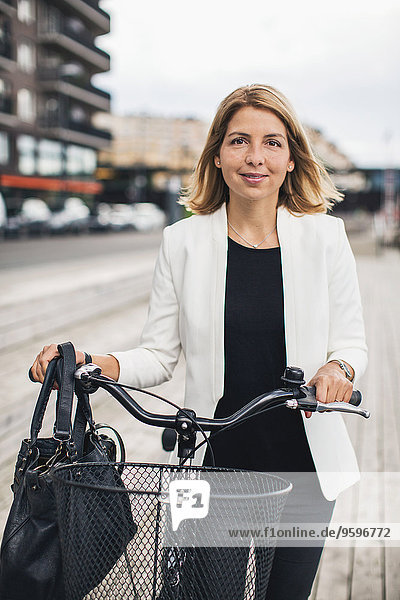 Porträt einer Geschäftsfrau mit Fahrrad in der Stadt