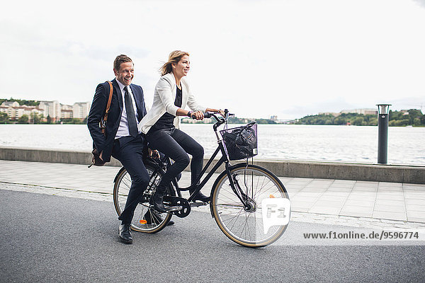 Glückliche Geschäftsleute auf dem Fahrrad in der Stadtstraße