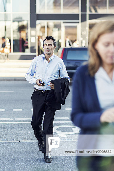 Full length of businessman crossing city street