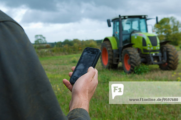 Männliche Landwirte halten Smartphone auf dem Feld hoch