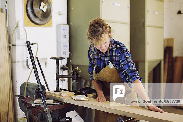 Junge Handwerkerin beim Prüfen von Holz in der Pfeifenorgel-Werkstatt