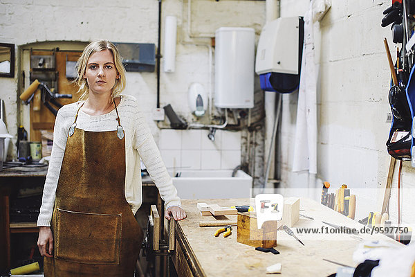 Porträt einer jungen Handwerkerin auf der Werkbank in der Orgelwerkstatt