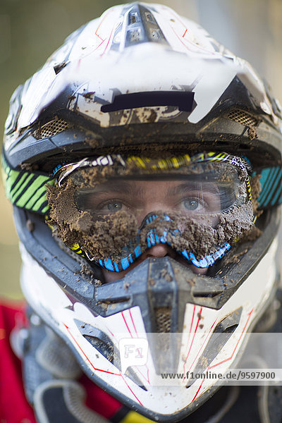 Nahaufnahme des männlichen Motocross-Rennfahrers mit schlammigen Helm und Brille