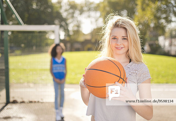 Porträt einer jungen Frau  die Basketball hochhält.