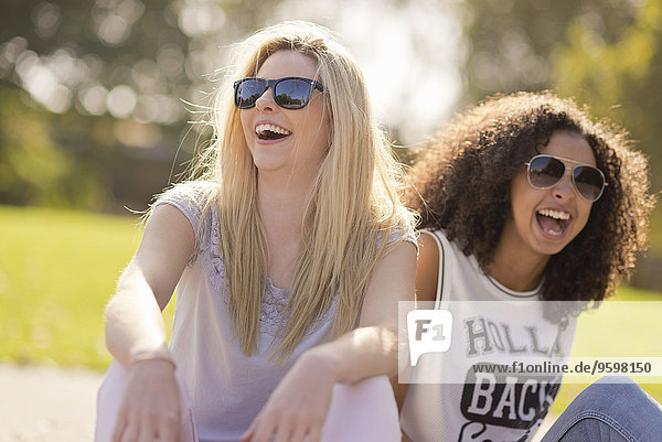 Zwei junge Freundinnen lachend im Park