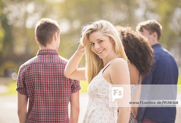 Junge Frau mit Freunden im Park mit Blick über die Schulter