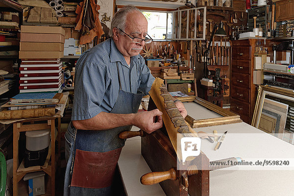Senior Mann repariert zerbrechlichen antiken Buchrücken in traditioneller Buchbinderei