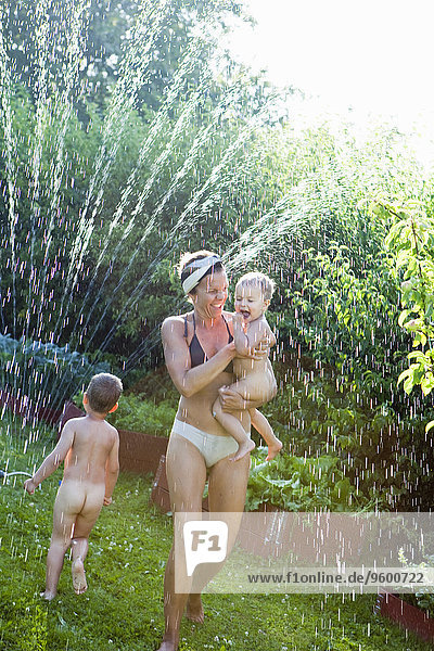 Mother and children playing with water in garden