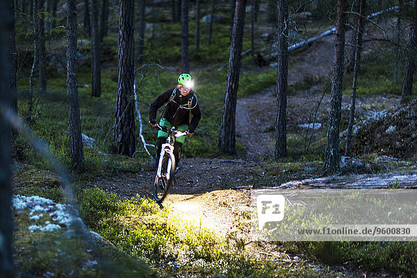Woman cycling through forest
