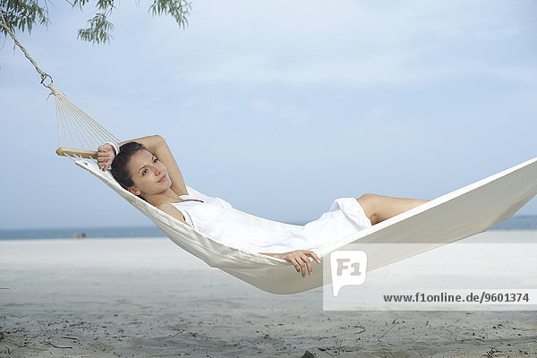 Junge Frau liegt in einer Hängematte am Strand