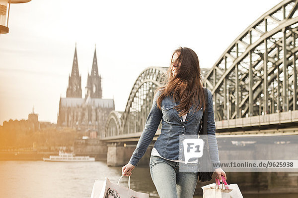 Deutschland  Köln  junge Frau mit Einkaufstaschen vor der Hohenzollernbrücke