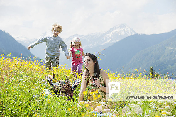Young woman and her two children having fun on alpine meadow