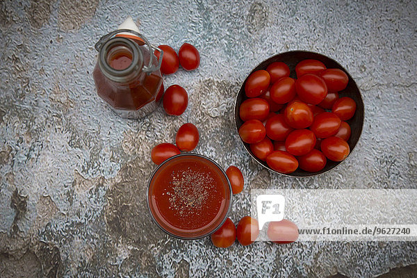 Glas und Flasche Tomatensaft und Tomaten