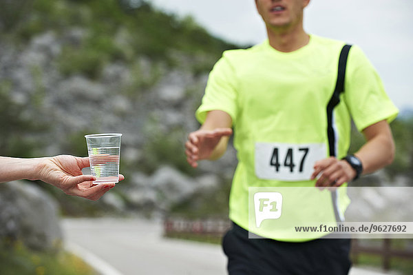 Italien  Trentino  Mann  der bei einem Laufwettbewerb in der Nähe des Gardasees eine Tasse Wasser erhält.