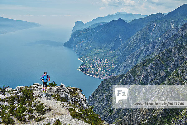 Italy  Trentino  man running on mountain peak at Lake Garda