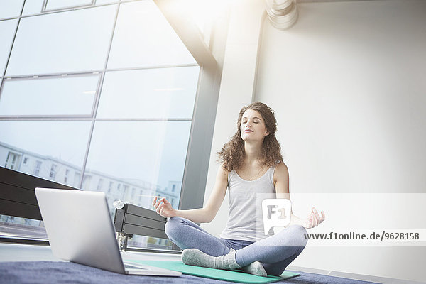 Frau beim Yoga mit Laptop