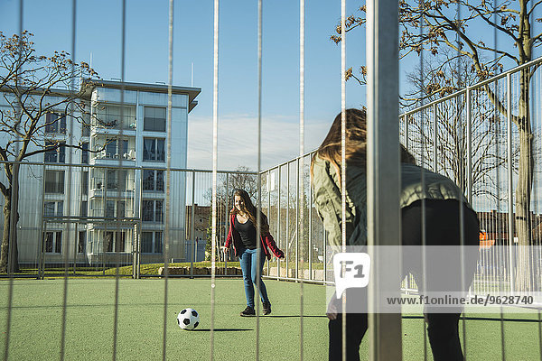 Zwei Teenager-Mädchen auf dem Sportplatz beim Fußballspielen