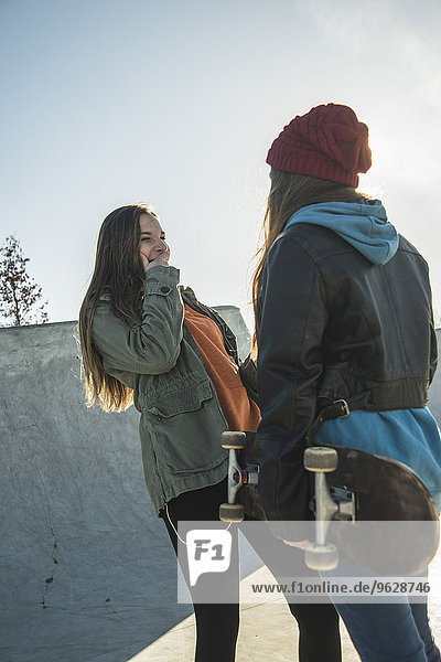 Two teenage girls in skatepark talking