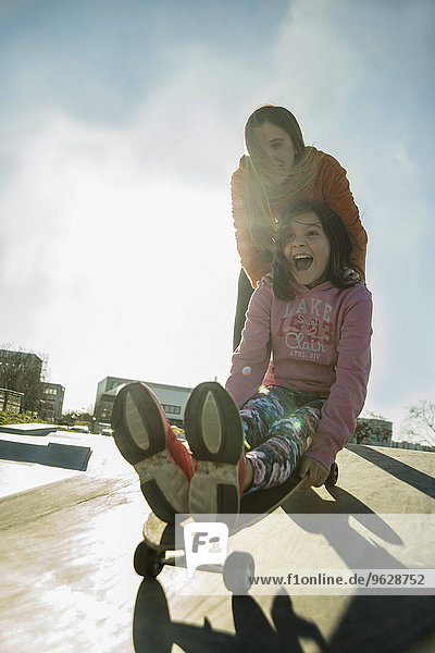 Teenager Mädchen schiebt Mädchen auf Skateboard