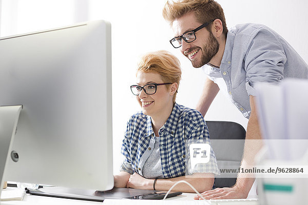Smiling young woman and man at desk in office
