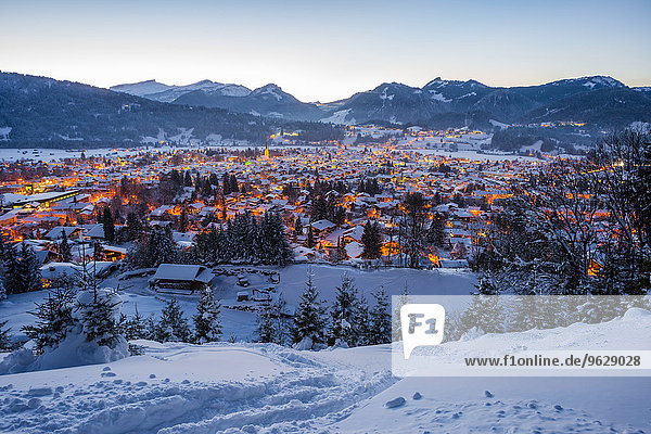Deutschland  Bayern  Blick auf das schneebedeckte beleuchtete Oberstdorf vor den Allgäuer Alpen