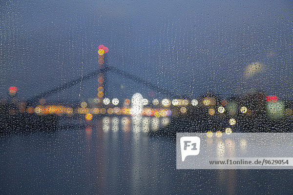 Deutschland,  Düsseldorf,  Medienhafen bei Nacht gesehen durch Fenster mit Regentropfen