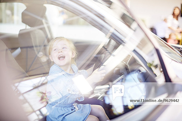 Glückliches Mädchen beim Autohändler im Auto