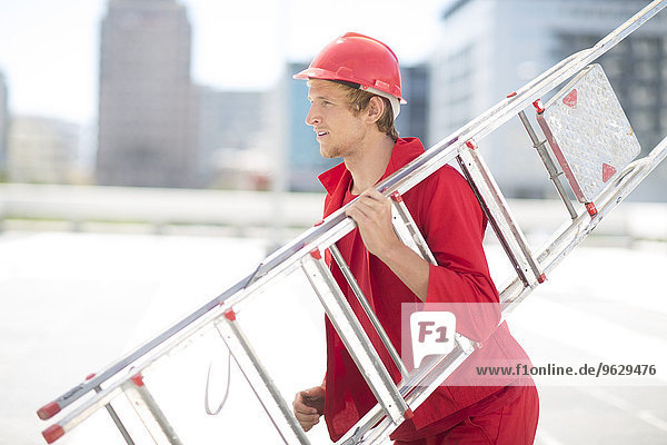 Worker with ladder and safety helmet dressed in red