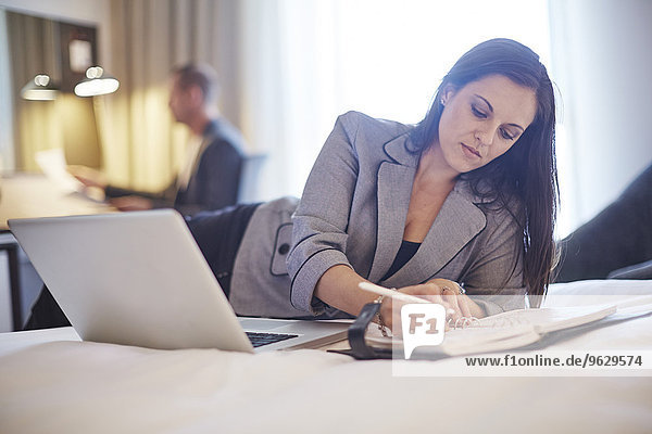 Businesswoman working on bed in hotel room