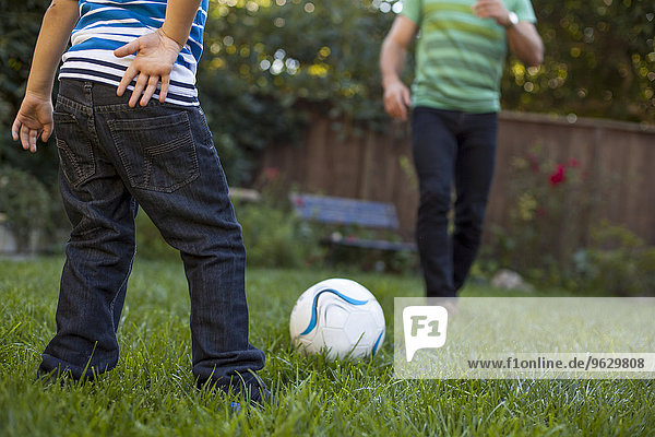 Vater und Sohn spielen Fußball im Garten