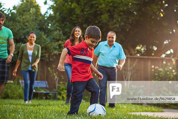 Drei Generationen Familie spielen Fußball im Garten