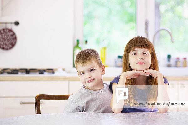 Porträt von Schwester und Bruder am Küchentisch sitzend