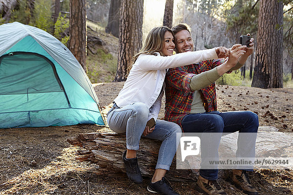 Junges Camping-Pärchen mit Smartphone Selfie im Wald  Los Angeles  Kalifornien  USA
