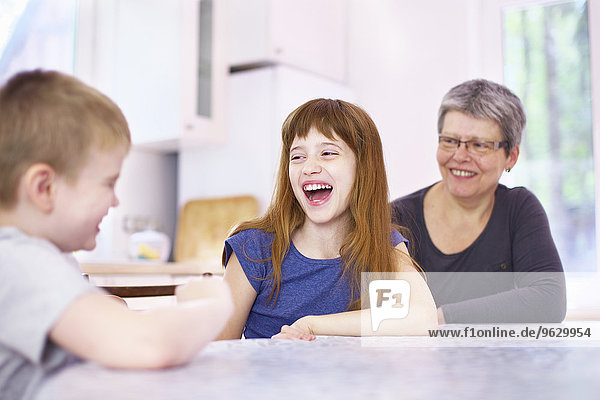 Großmutter und Enkelkinder lachen am Küchentisch