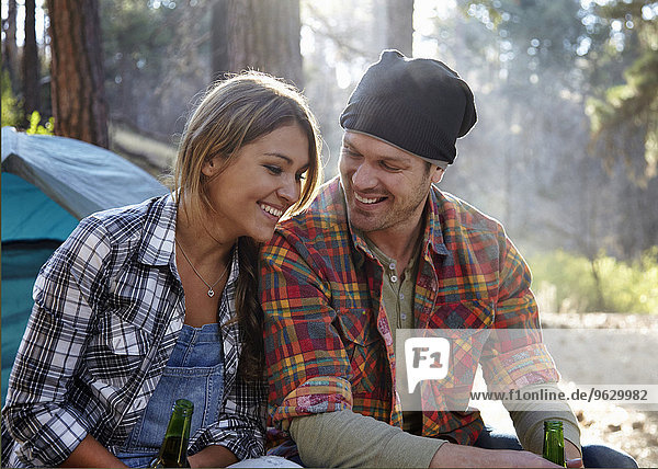 Young couple chatting by campfire in forest  Los Angeles  California  USA
