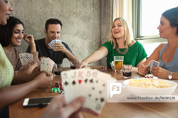Group of friends playing cards around table