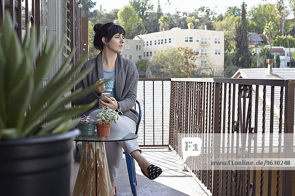 Frau mit Smartphone auf dem Balkon