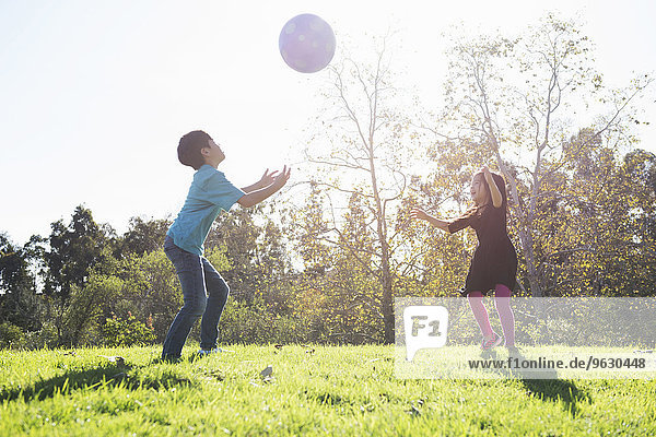 Bruder und Schwester beim Fangen mit Ball im Park